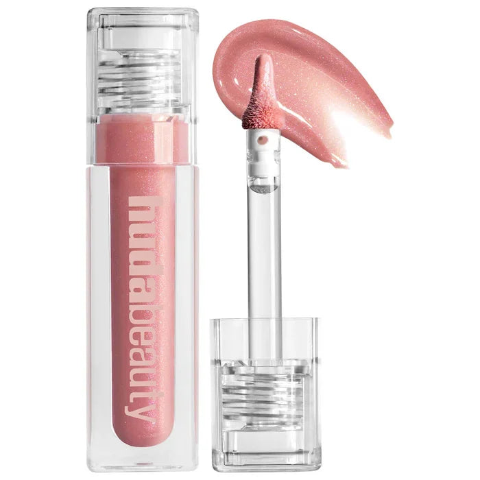 Huda Beauty hydrating lip gloss in shimmering soft pink with applicator wand and creamy liquid texture swatch.