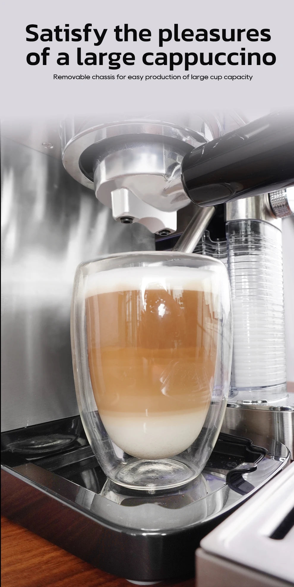 Stainless steel espresso machine filling a large glass cappuccino cup with removable base for tall drink capacity.