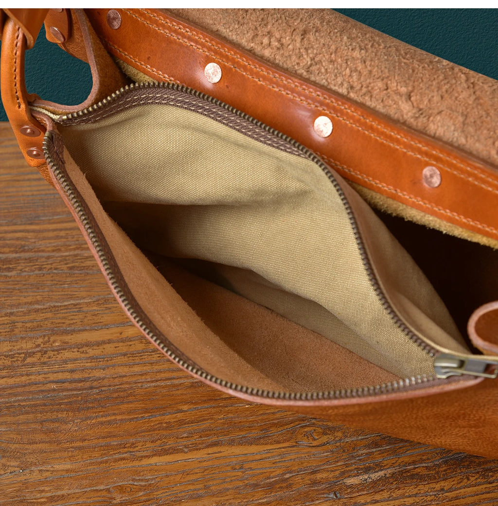 PNDME vintage handmade cowhide leather messenger bag with rivet details and tan canvas interior lining.