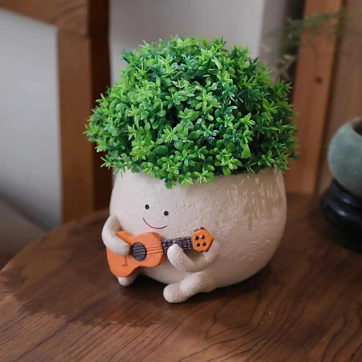 Mini hanging succulent planter pot with smiling face, green plant and small toy guitar detail