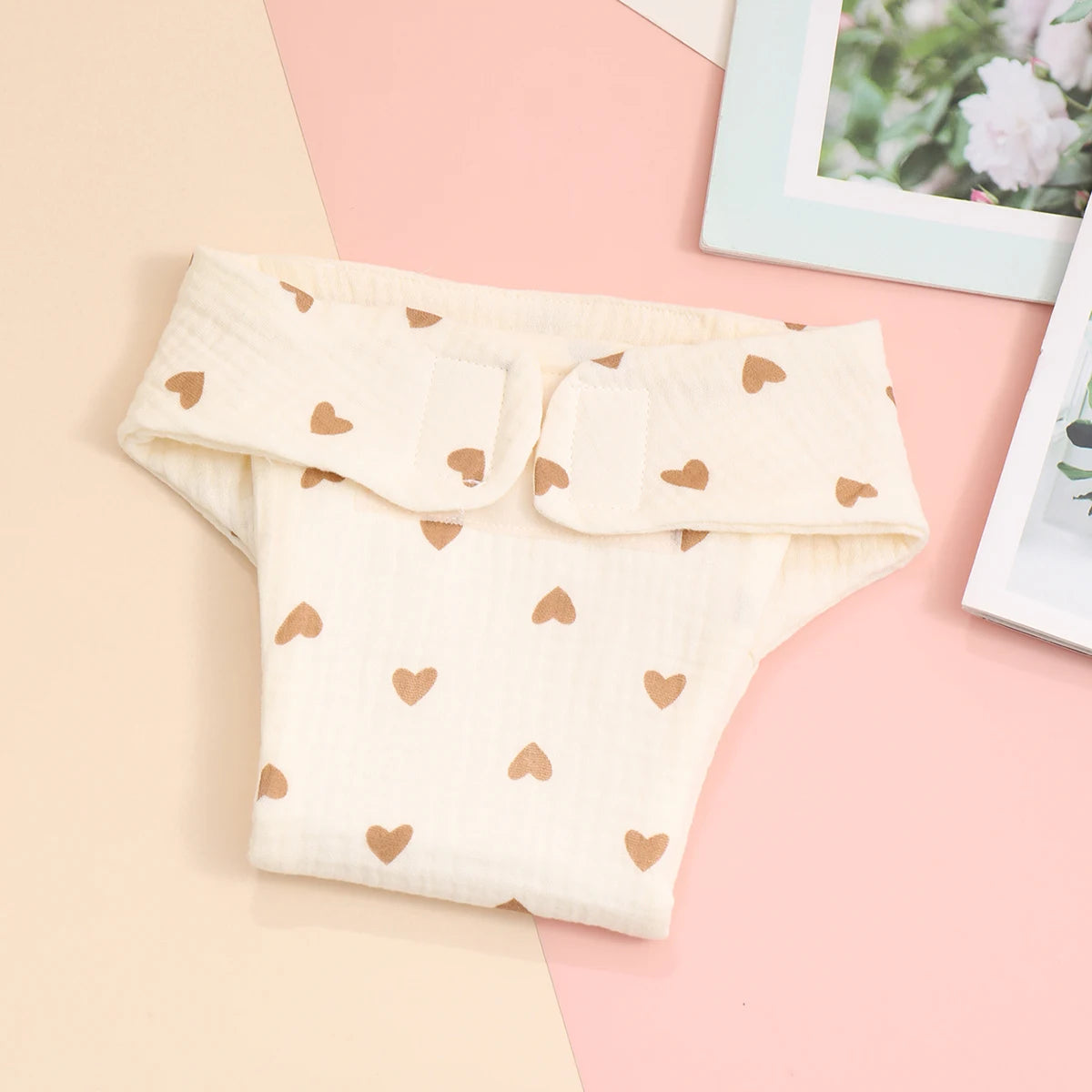Cream-colored baby diaper cover made of soft muslin cotton with a brown heart print pattern.