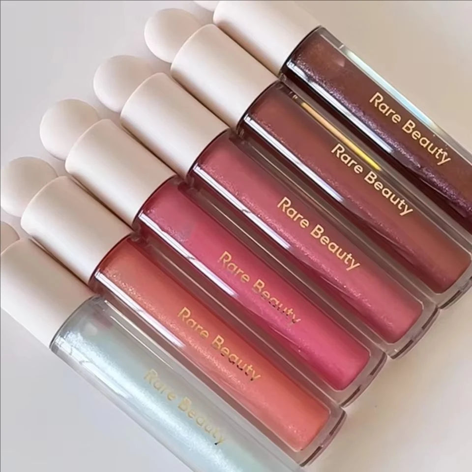 Rare Beauty Soft Pinch Tinted Lip Oil collection featuring various glossy, moisturizing shades in clear tubes.