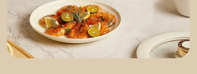 White non-stick electric cooking pot with cooked seafood dish and lemon slices