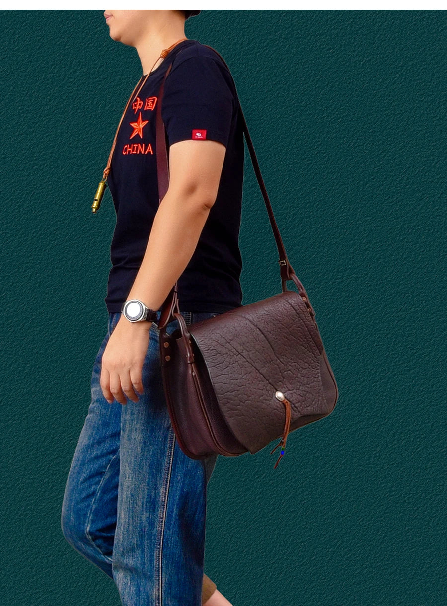 Vintage brown genuine cowhide leather messenger bag with flap closure, adjustable strap, and artisan textured finish.
