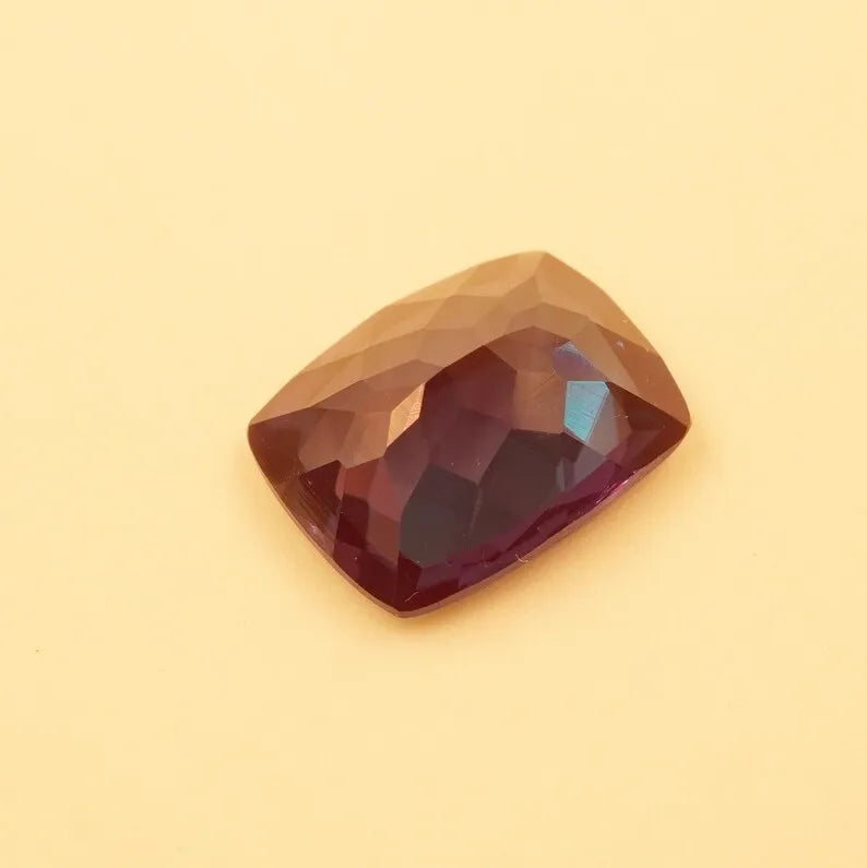 Faceted cushion-cut alexandrite gemstone, dark red-brown with subtle teal flash