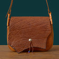 Vintage brown genuine cowhide messenger bag with textured leather flap, metal stud closure, and beaded leather cord.