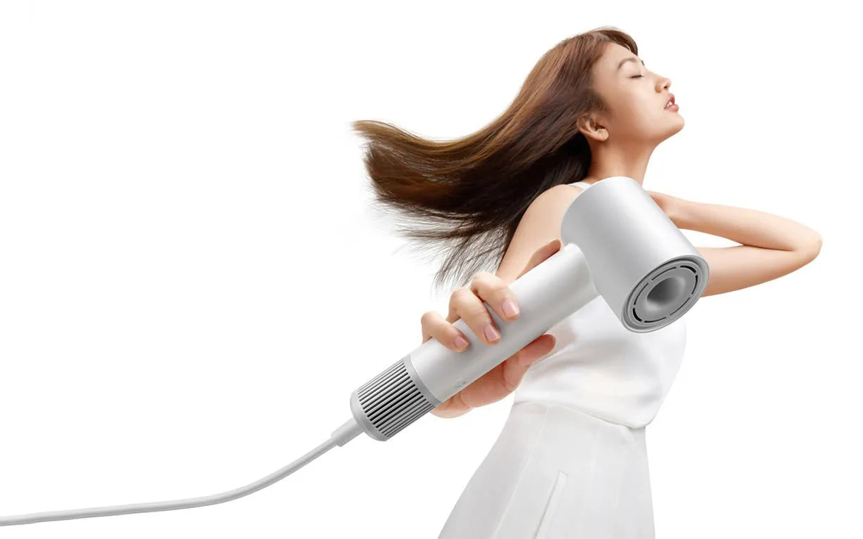 Woman using a white MIJIA H501SE high-speed ionic hair dryer for fast, professional hair styling at home.