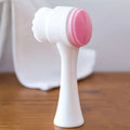 Double-sided facial cleansing brush with pink silicone exfoliator and soft bristles for manual daily pore care.