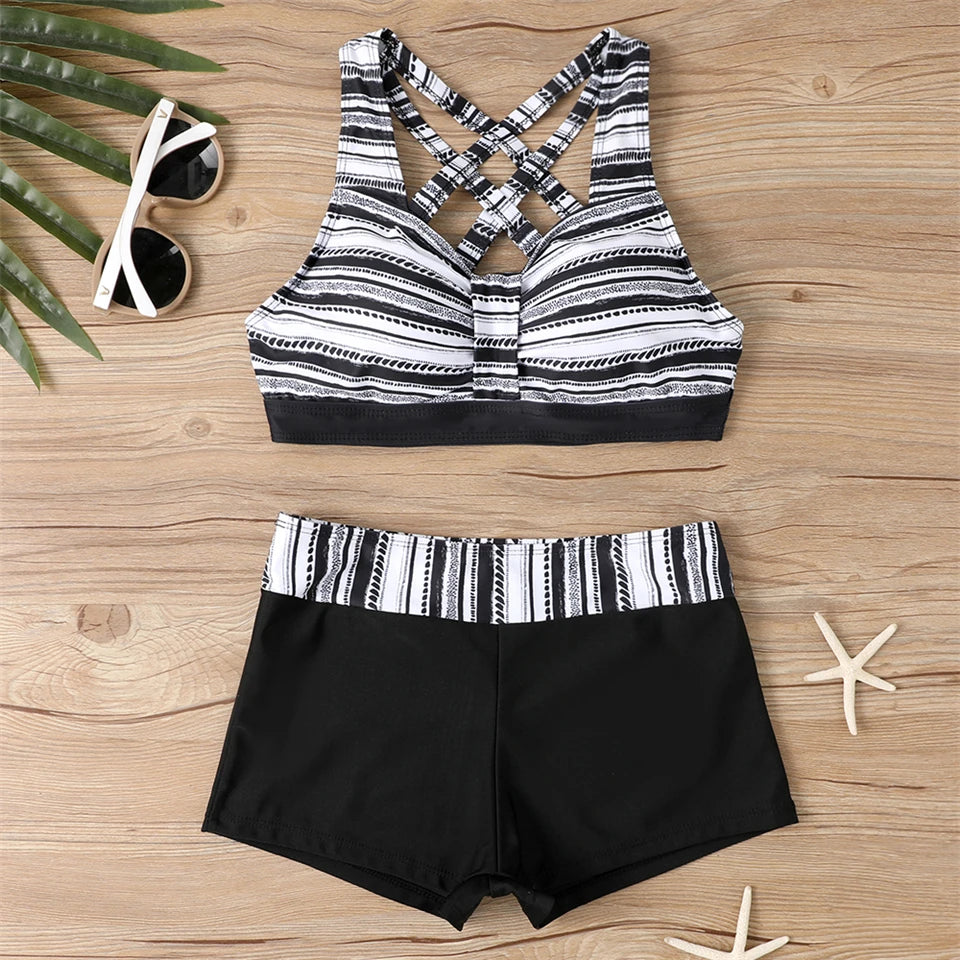 Tidesmit black and white striped high-waisted bikini with a crisscross sports bra top on a wooden background.