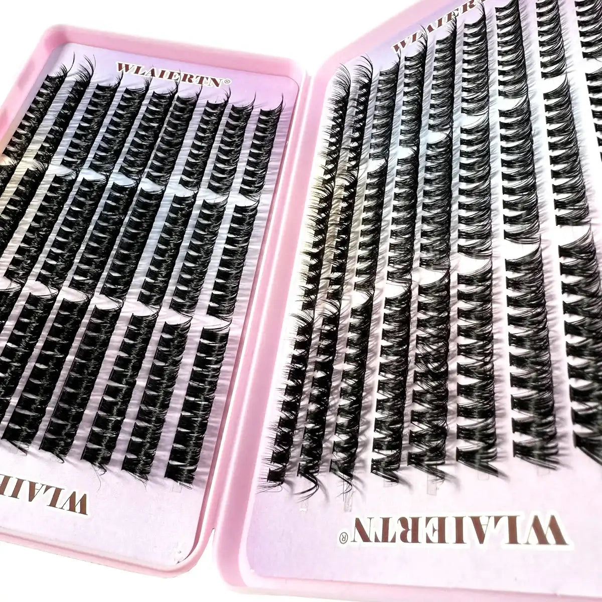 Individual black synthetic lash clusters arranged in rows within a pink plastic palette for professional application.
