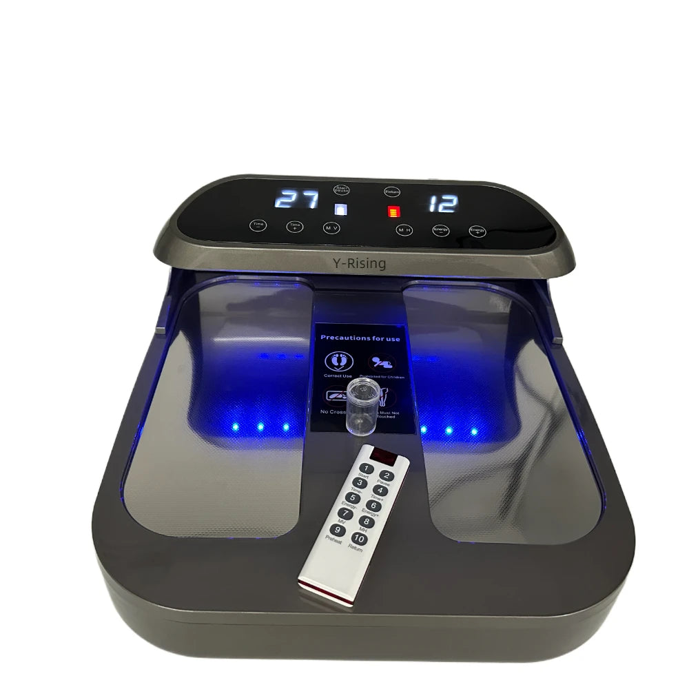 Gray ionic foot detox machine with LED displays, blue indicator lights, a clear salt scoop, and a remote control.