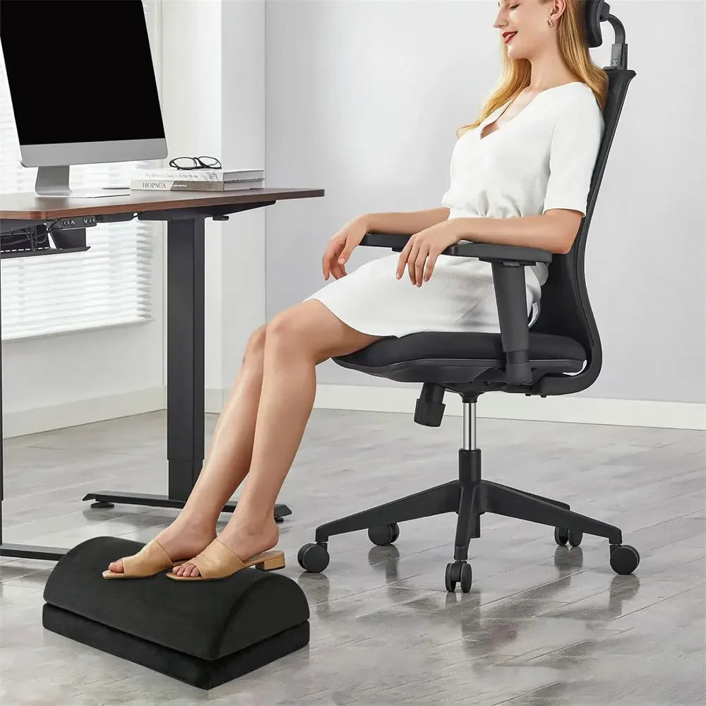 Woman using a black 2-in-1 adjustable ergonomic foot rest under a desk for back, knee, and lumbar pain relief.