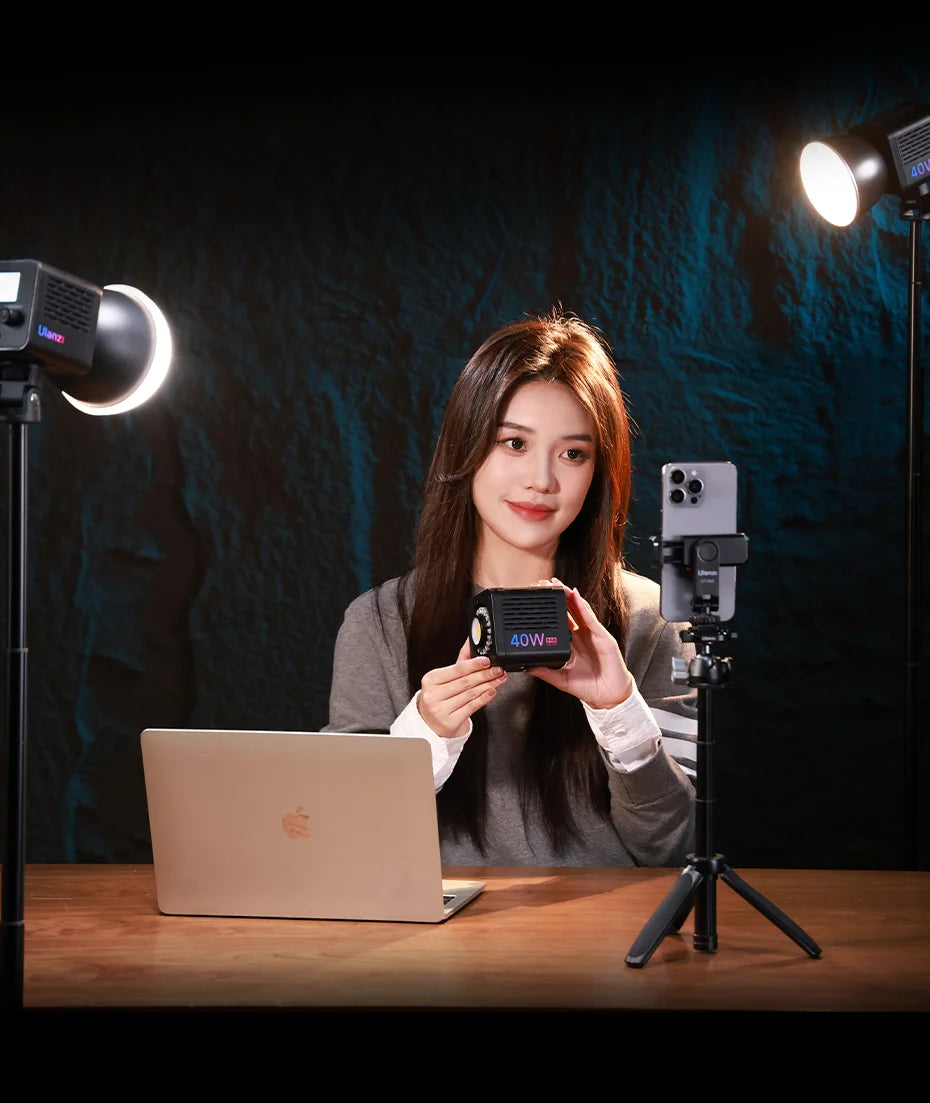 Compact black 40W LED video light cube held by a woman, used for professional lighting in content creation.