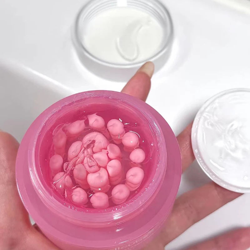 Open pink jar containing small pink cream capsules suspended in a clear, lightweight gel-like serum.