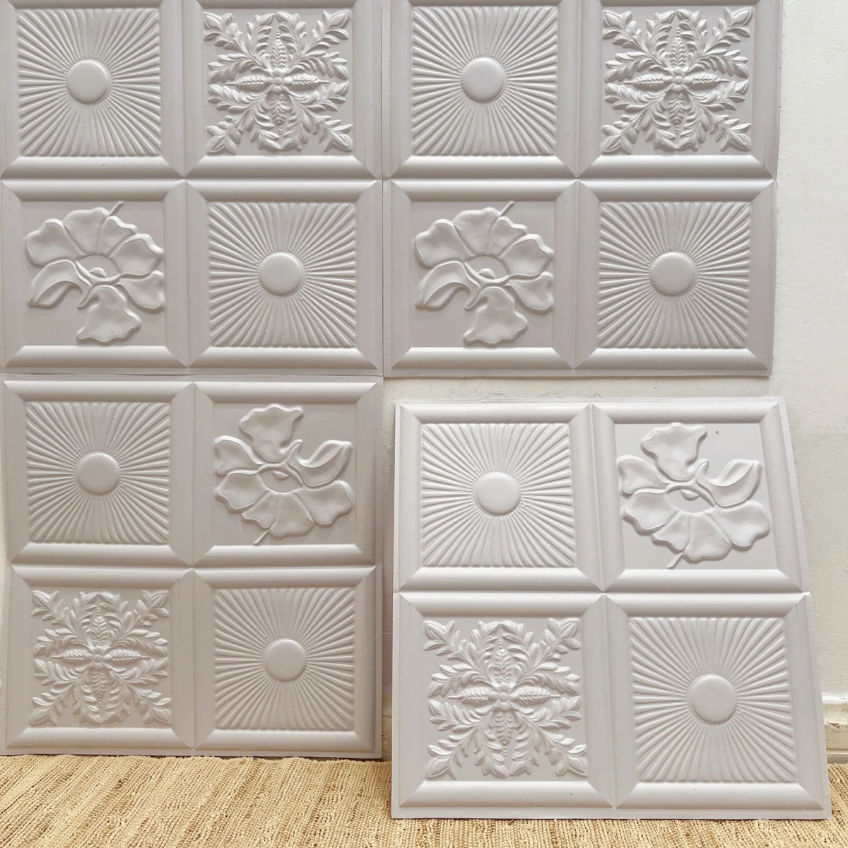 Peel-and-stick embossed tile backsplash set in matte white, featuring raised geometric floral squares