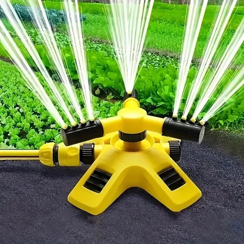Yellow 360° rotating sprinkler head with four black nozzle arms spraying over a garden lawn