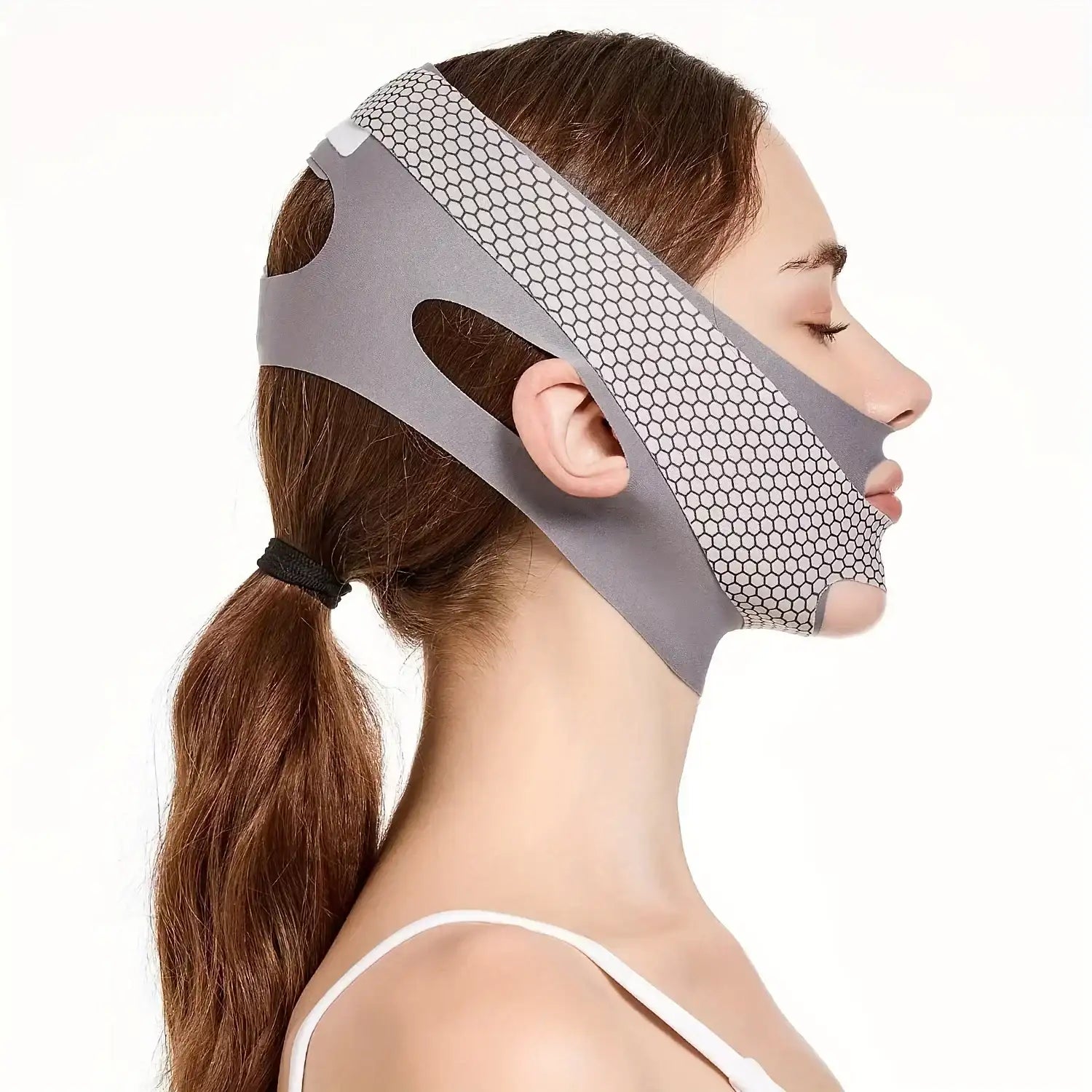 Woman wearing a grey, honeycomb-patterned V-line face slimming bandage strap.