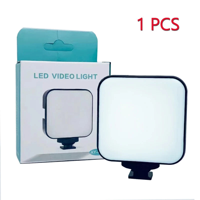 Small, square LED video light with a white panel and black base, standing next to its turquoise and white box.