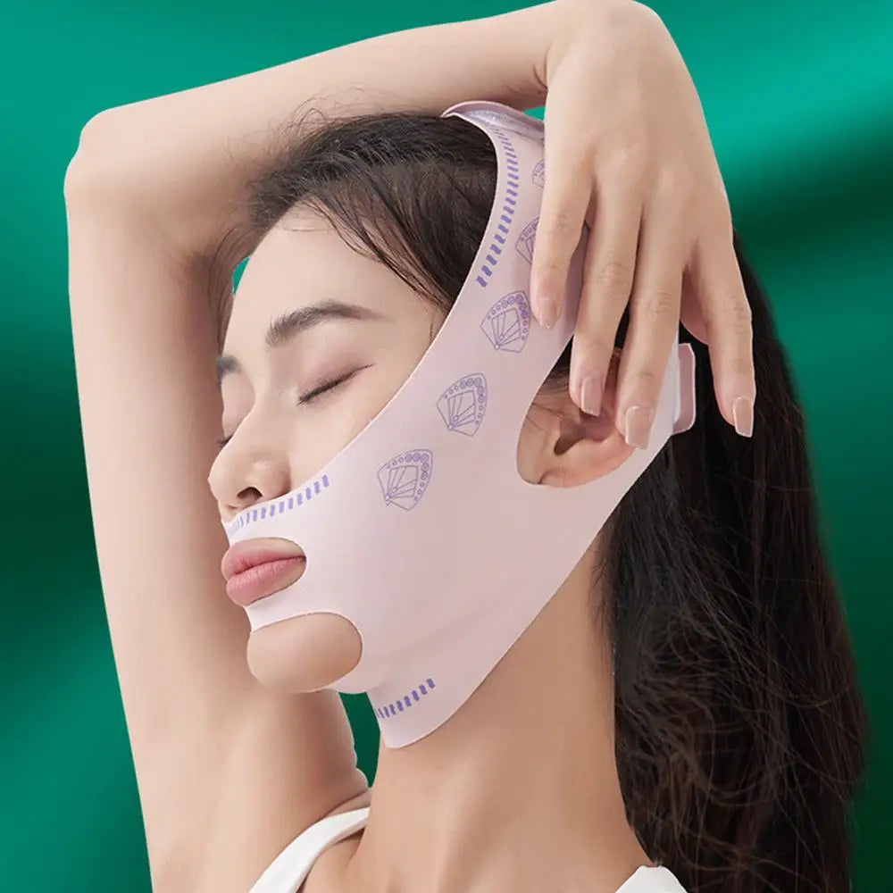 A woman wearing a pale pink, fabric V-line face lifting mask with purple fan-shaped patterns on a green background.