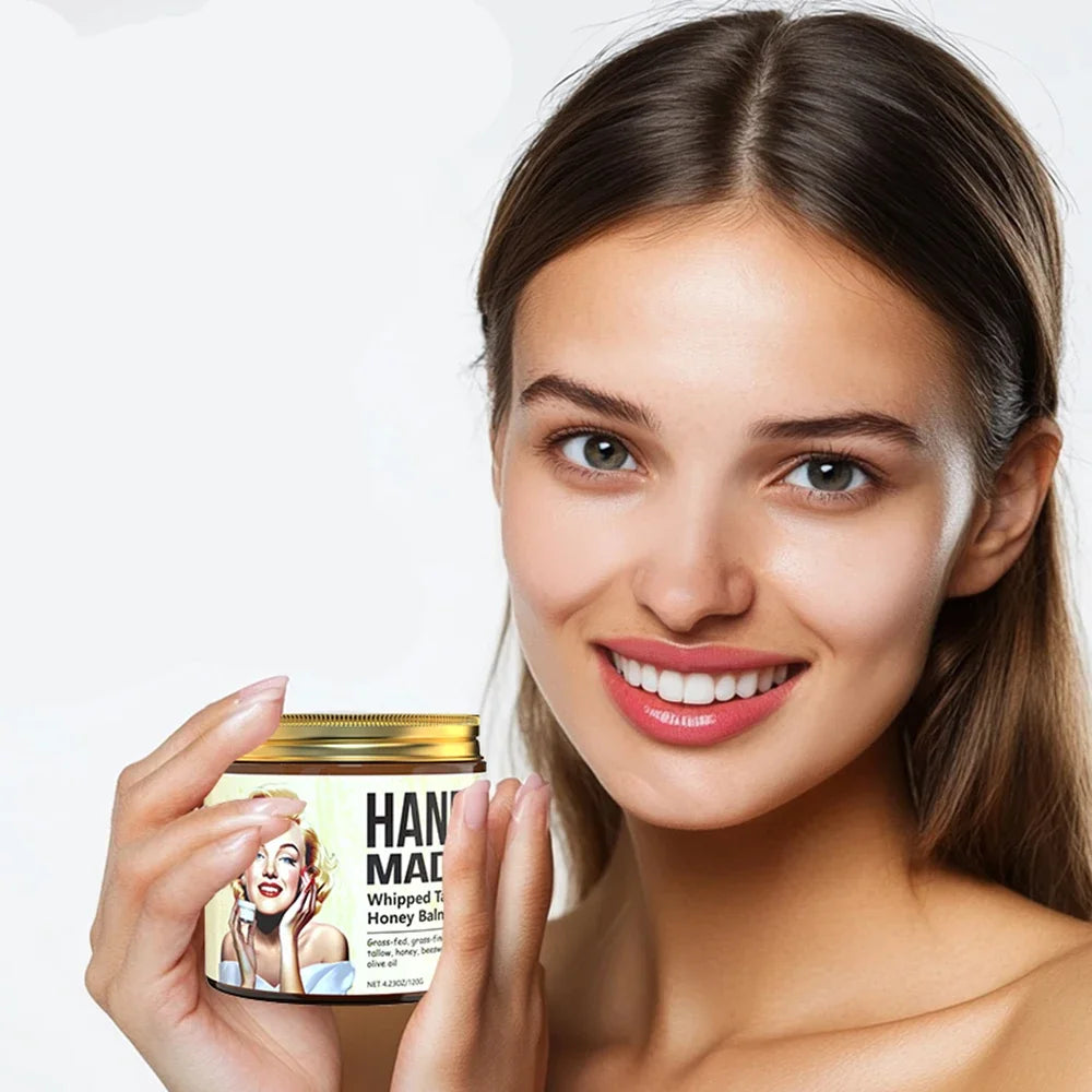 Woman smiling while holding an ENVISHA jar of handmade whipped tallow honey face cream for nourishing skin care.