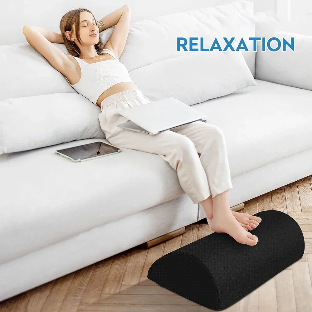 Black, semicircular foam footrest cushion on the floor, used to support feet while sitting on a couch.