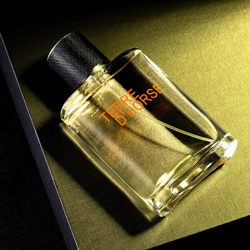 Terre d'Horse perfume in a rectangular glass bottle with a textured black cap on a gold surface.