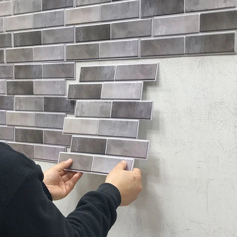Peel-and-stick backsplash tiles in gray brick pattern; hands applying sheet