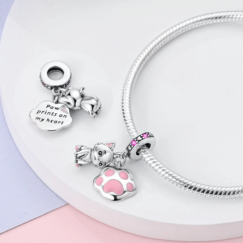 Sterling silver dog and cat paw charms for DIY bracelets, featuring pink enamel accents and engraved pet sentiments.