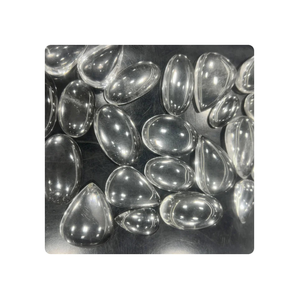 Assorted cushion-cut crystal quartz gemstones piled together, translucent gray