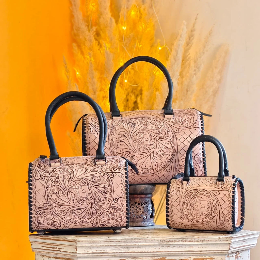 Hand-tooled floral leather trunks in set of three, featuring black handles, trim, and unique playing card detail.