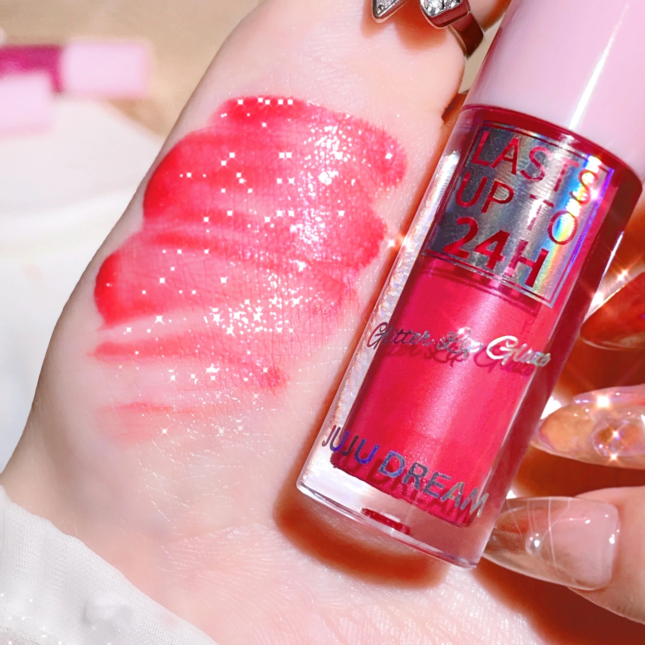 Long-lasting, waterproof glitter lip glaze in vibrant pink, shown as a shimmering swatch on hand. Glossy lip makeup.