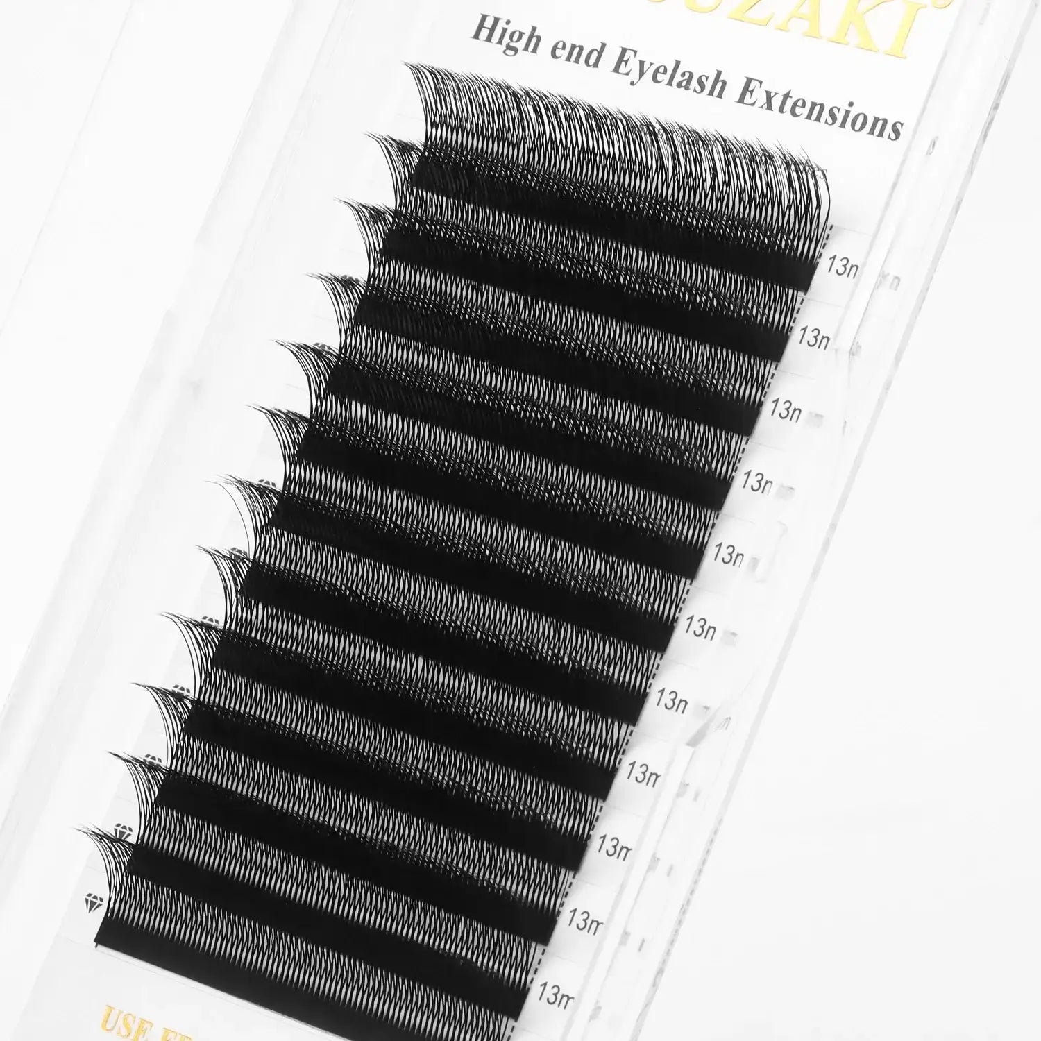 Tray of black, C-curl eyelash extensions, 13mm length, arranged in rows on a clear adhesive strip for application.