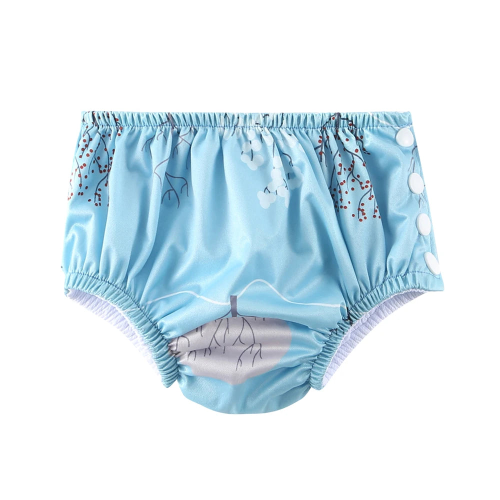 Reusable baby swim diaper in light blue with white tree and berry pattern, side-snap closure.