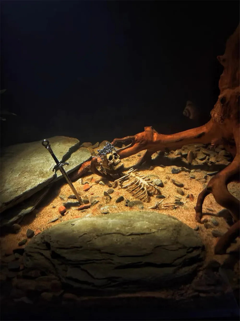 Miniature 1:12 faux skeleton model with sword in aquarium; realistic lizard tank decor for a spooky reptile habitat.