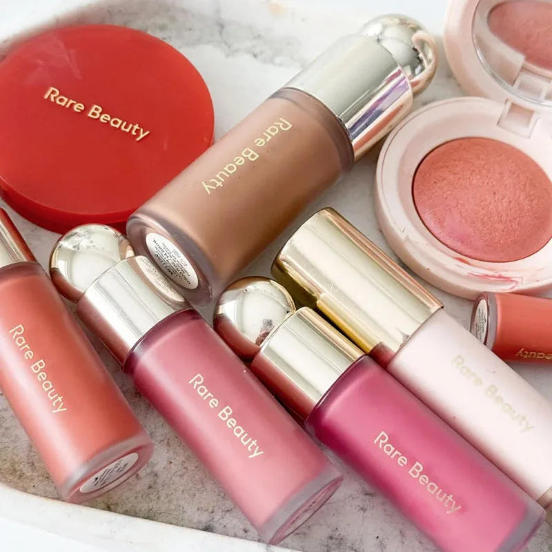 Rare Beauty collection featuring liquid blush, highlighter, and powder compacts in various shades and silky textures.