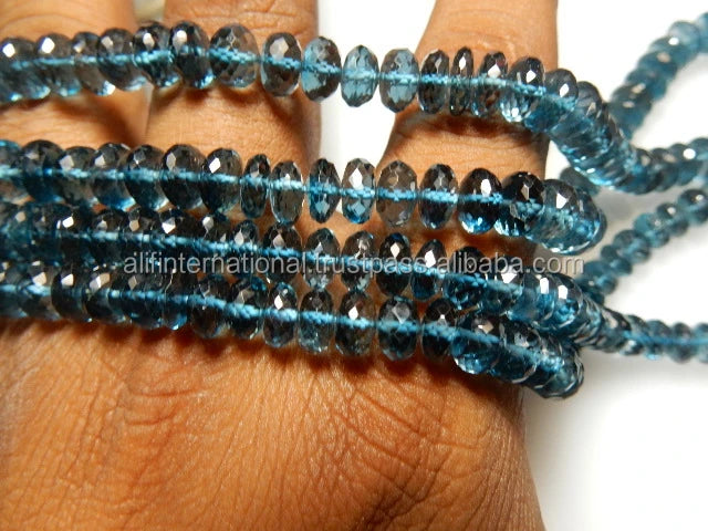 Blue faceted rondelle gemstone bead strands draped on hand, loose beads for crafting.