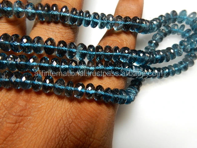 Blue faceted rondelle bead strand looped across hand, loose gemstone beads for crafting.