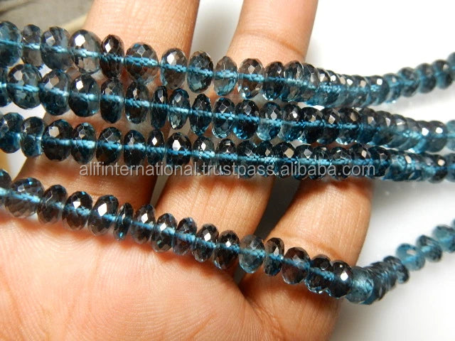 Blue faceted rondelle bead strands with sparkle on fingers, loose gemstone beads.