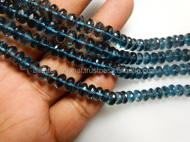 Blue faceted rondelle gemstone bead strands close-up on hand, loose beads for crafting.